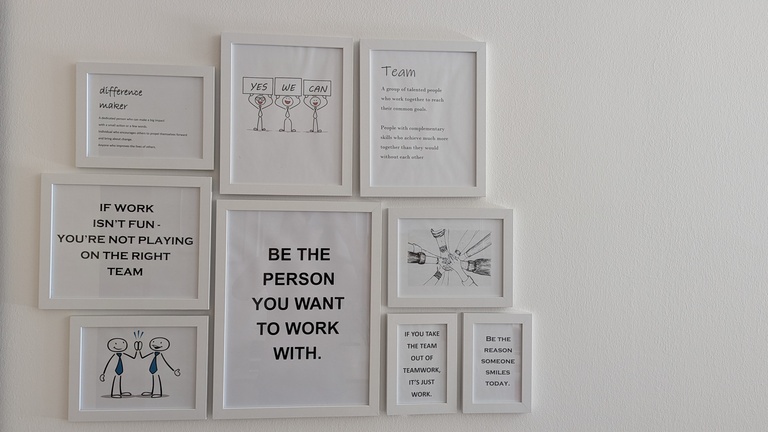 An einer Wand hängen viele Sprüche und Bilder in weißen Bilderrahmen.