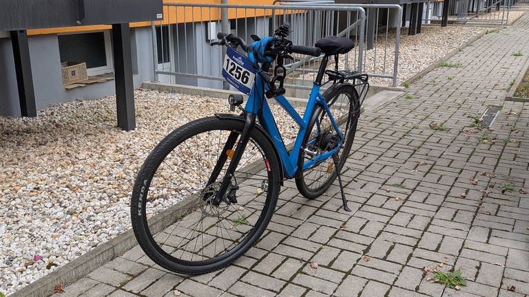 Ein blaues Fahrrad steht in einem Hof.